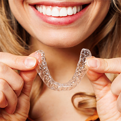 patient holding invisalign clear aligner smiling
